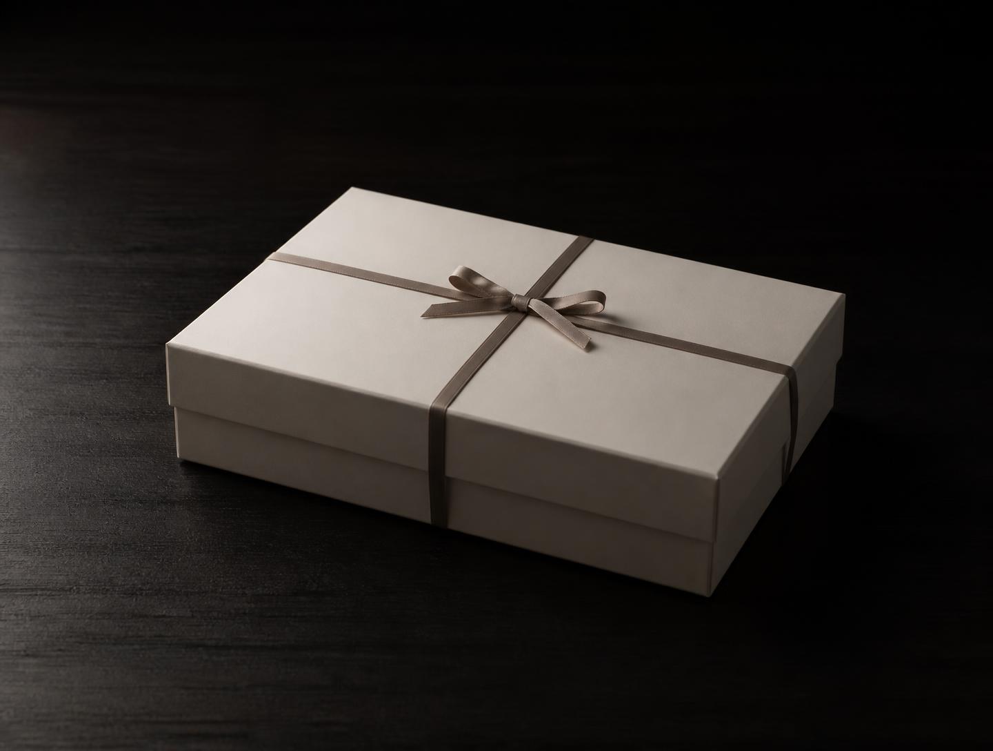 Coffret ivoire neutre fermé d'un ruban taupe, sans mention du contenu